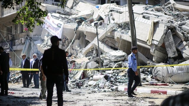 Polizisten und Einsatzkräfte stehen vor den Trümmern eines Gebäudes in Gaza, welches bei israelischen Luftangriffen auf die Stadt zerstört wurde. Polizisten und Einsatzkräfte stehen vor den Trümmern eines Gebäudes in Gaza, welches bei israelischen Luftangriffen auf die Stadt zerstört wurde.