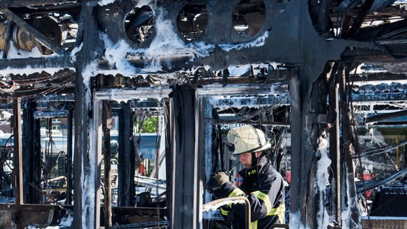 Ein Feuerwehrmann kontrolliert mit einer Wärmebildkamera ausgebrannte Busse auf einem Betriebshof im Stadtteil Wandsbek.