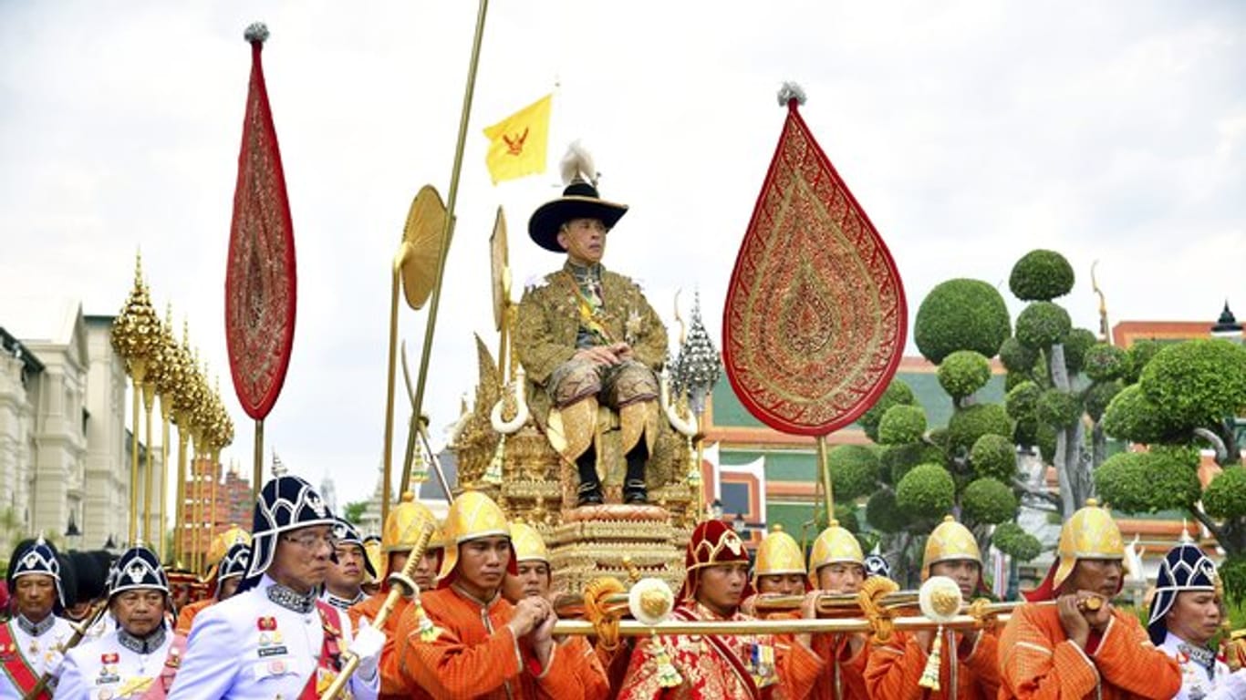 König Maha Vajiralongkornwird auf einer Sänfte durch die Straßen getragen.
