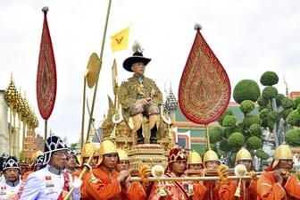 König Maha Vajiralongkornwird auf einer Sänfte durch die Straßen getragen.