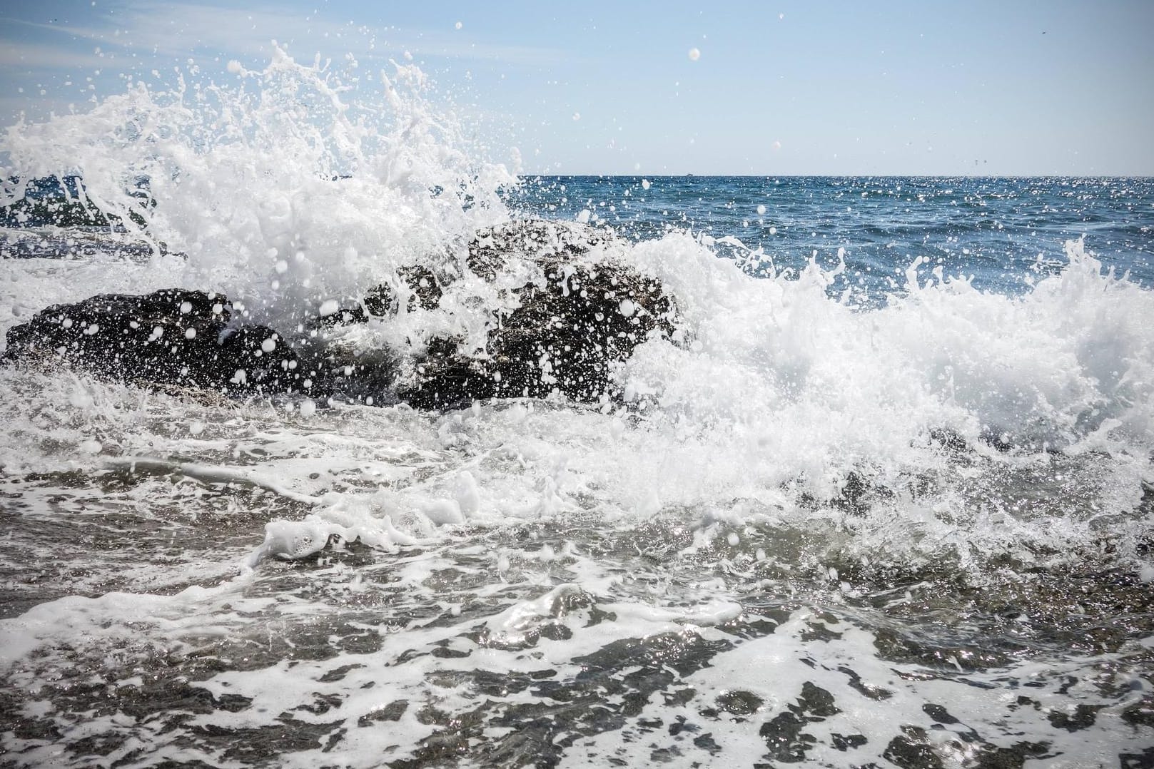 Brandung von Welle gegen Felsen auf Korsika (Symbolbild): Eine deutsche Touristin ist auf der Insel von einer Welle ins Meer gerissen worden und ertrunken.