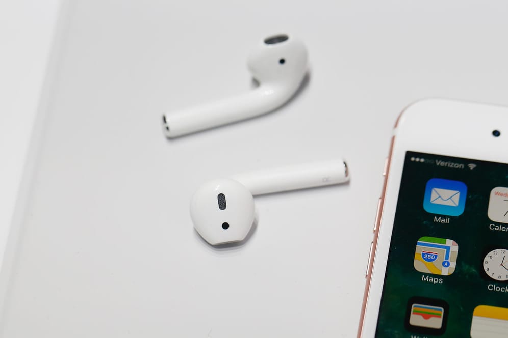 Apple AirPods neben einem iPhone: Die beliebten In-Ear-Kopfhörer sind zum Sport und im Alltag beliebt.