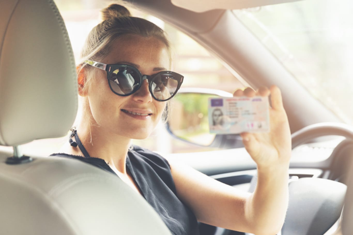 Eine stolze Absolventin zeigt ihren Führerschein.