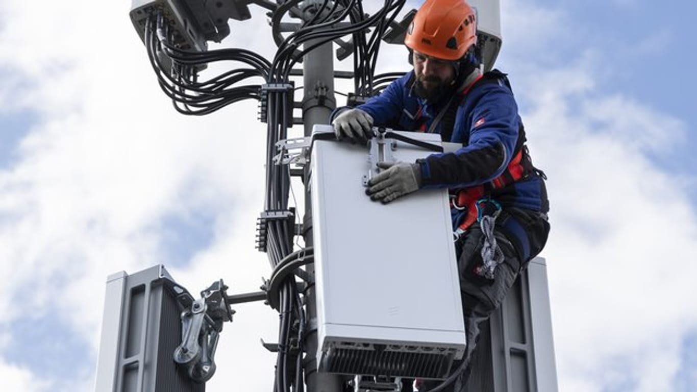 Ein Techniker installiert eine Antenne für das 5G-Funknetz auf einem Hausdach.