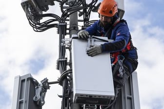 Ein Techniker installiert eine Antenne für das 5G-Funknetz auf einem Hausdach.