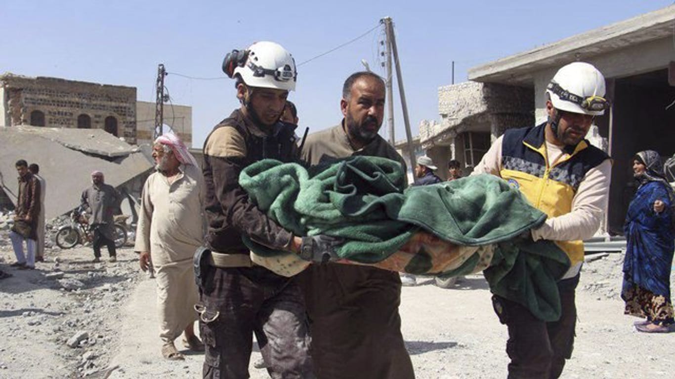 Mitglieder der sogenannten Weißhelme tragen in Idlib ein Opfer eines Luftangriffs auf einen Markt weg.
