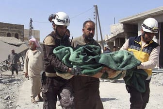 Mitglieder der sogenannten Weißhelme tragen in Idlib ein Opfer eines Luftangriffs auf einen Markt weg.