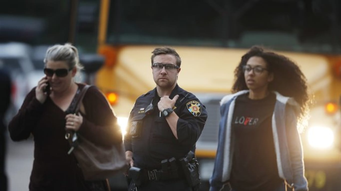 Ein Polizist schützt nach der Bluttat Schüler, die vor der angegriffenen Highschool aus einem Bus steigen.
