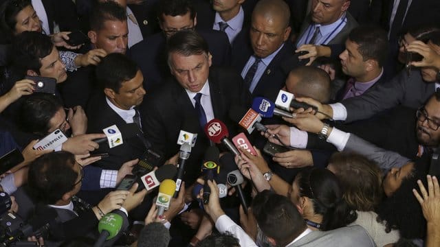 Brasiliens Präsident Jair Bolsonaro (M) spricht mit Journalisten, nachdem er das Dekret zum gelockerten Waffenrecht unterzeichnet hat. Brasiliens Präsident Jair Bolsonaro (M) spricht mit Journalisten, nachdem er das Dekret zum gelockerten Waffenrecht unterzeichnet hat.