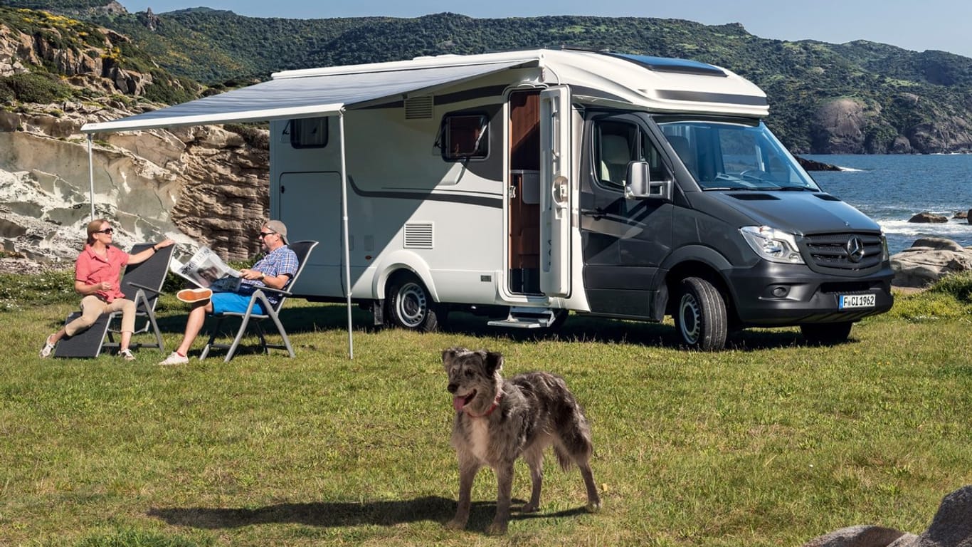 Camper sitzen vor einem Reisemobil: Wohnmobile für den nächsten Trip ans Meer können Urlauber auch mieten.