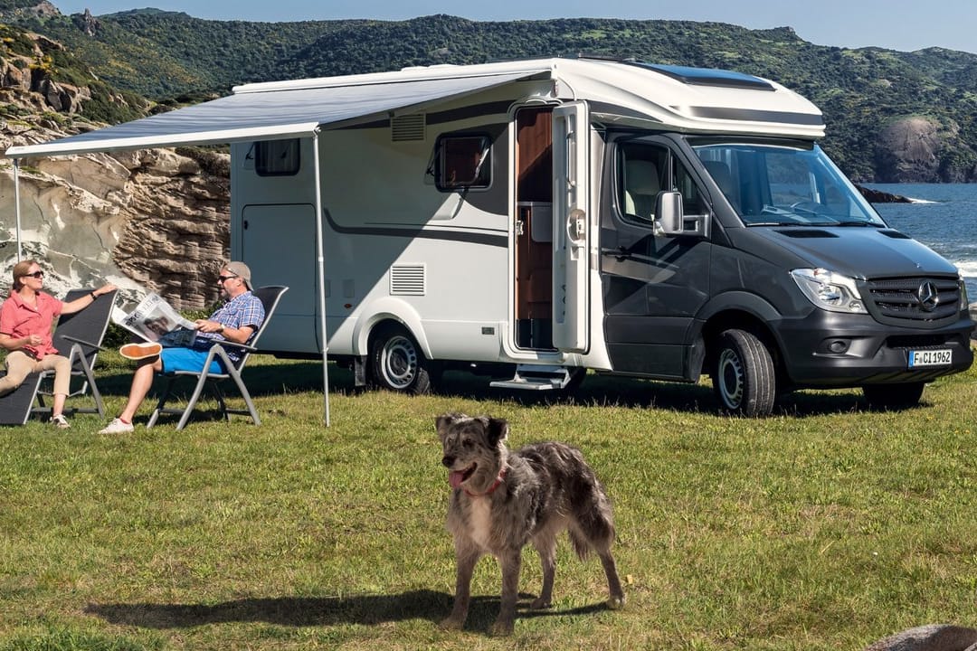 Camper sitzen vor einem Reisemobil: Wohnmobile für den nächsten Trip ans Meer können Urlauber auch mieten.