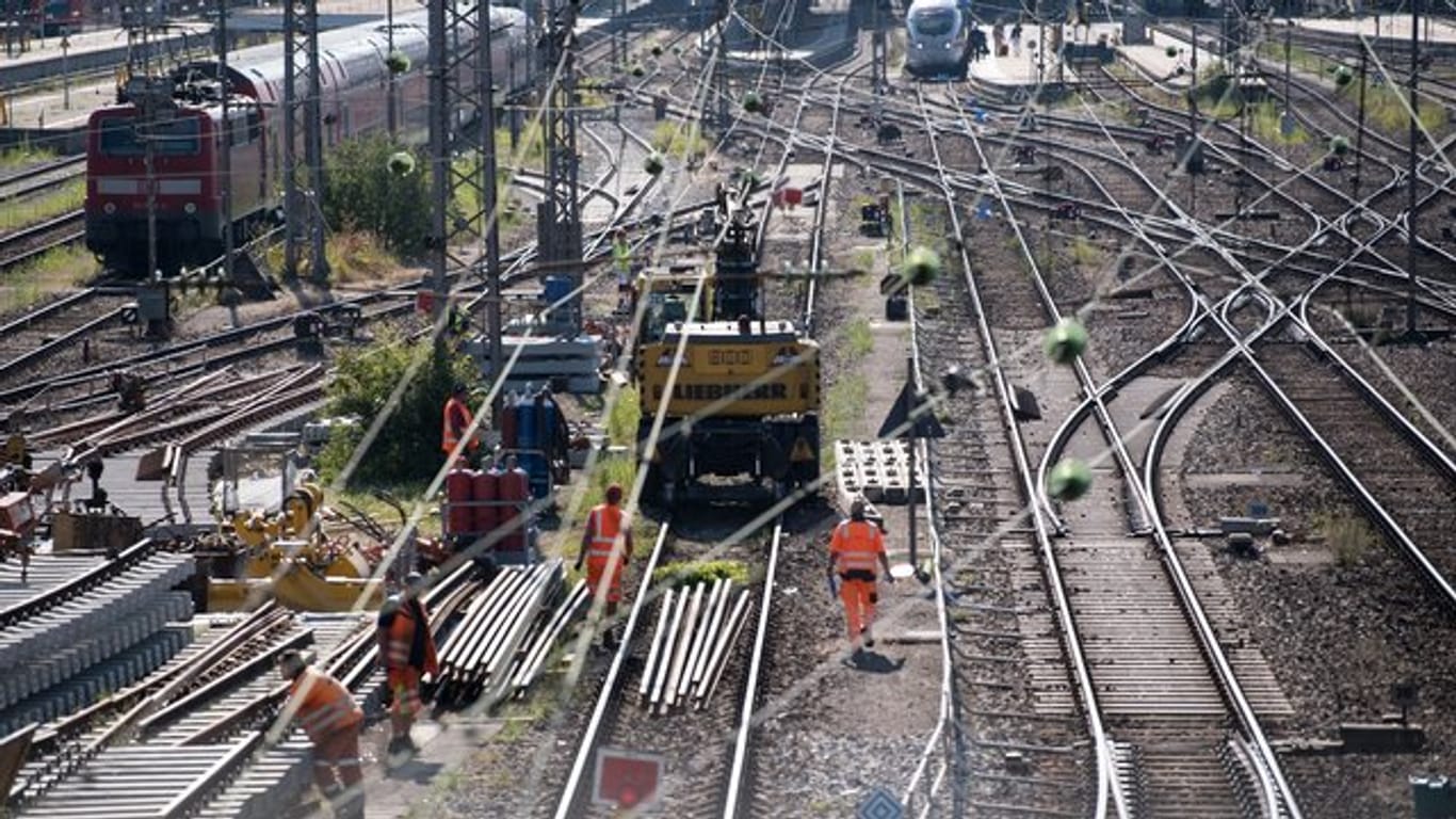 Bauarbeiter arbeiten an den Gleisen vor einem Bahnhof (Symbolbild): Die Bahn rechnet mit verpassten Anschlusszügen und Haltausfällen.