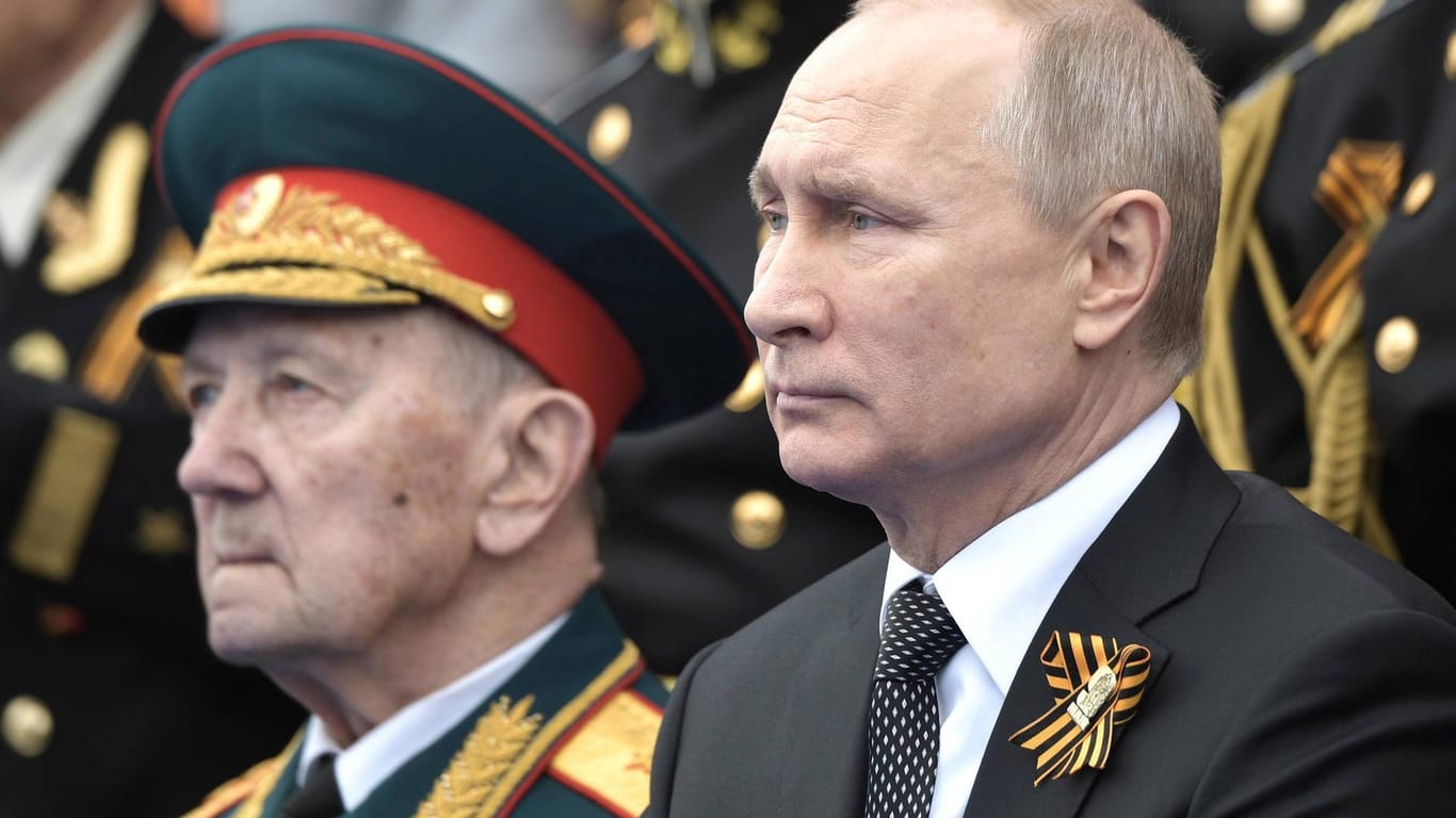 Wladimir Putin sitzt während der Militärparade in Moskau neben russischen Offizieren.