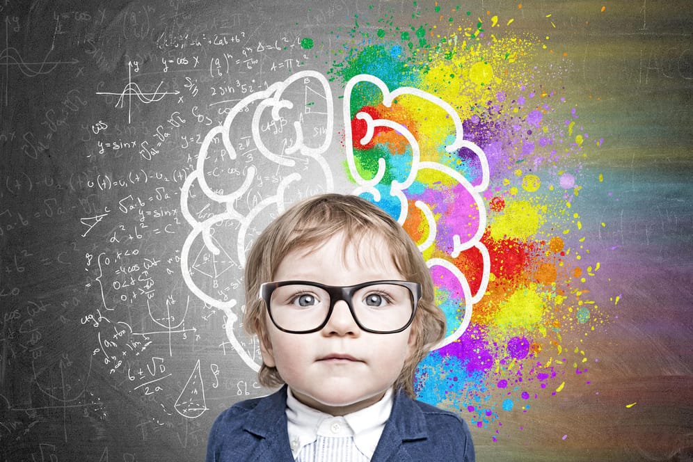 Ein kleines Kind steht vor einer Tafel auf der ein Gehirn und verschiedene Formeln gezeichnet sind.