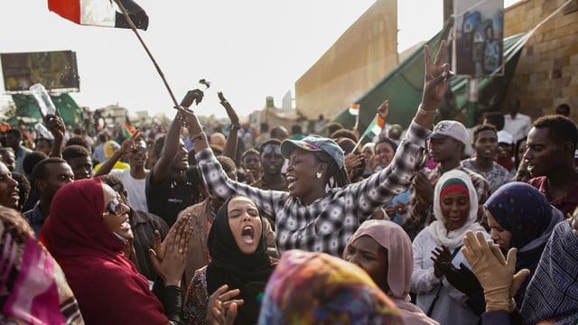 Sudanesische Demonstranten feiern die Verhaftung des langjährigen Präsidenten Omar al-Bashir durch die Streitkräfte außerhalb des Verteidigungsministeriums. Sudanesische Demonstranten feiern die Verhaftung des langjährigen Präsidenten Omar al-Bashir durch die Streitkräfte außerhalb des Verteidigungsministeriums.