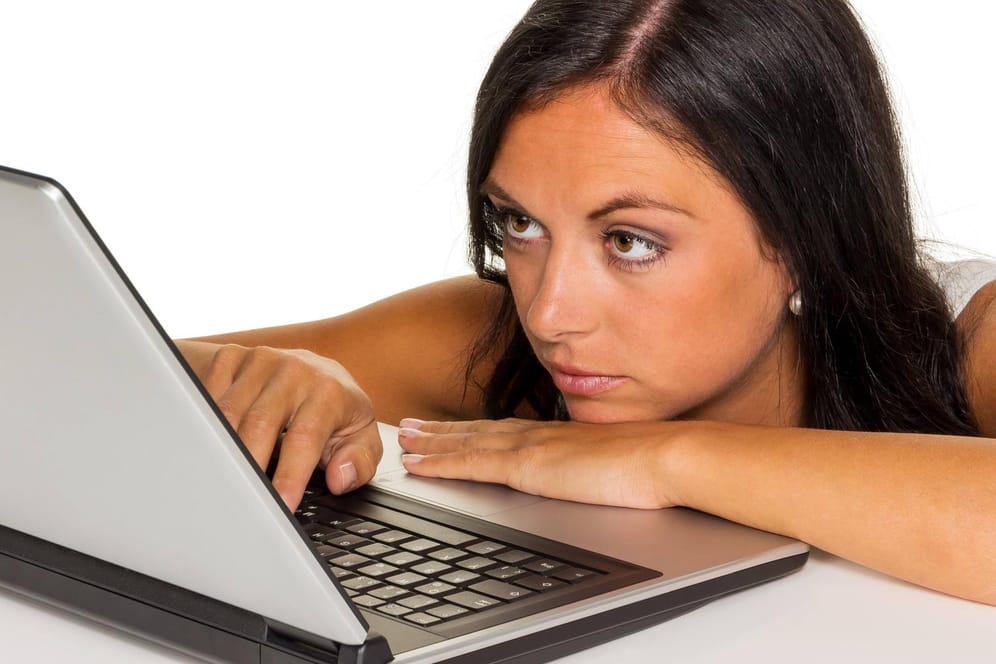 Eine Frau blickt genervt auf ihren Laptop: Wenn das Postfach von Spam-Mails geflutet wird, ist das nicht nur ärgerlich. Es ist auch gefährlich.