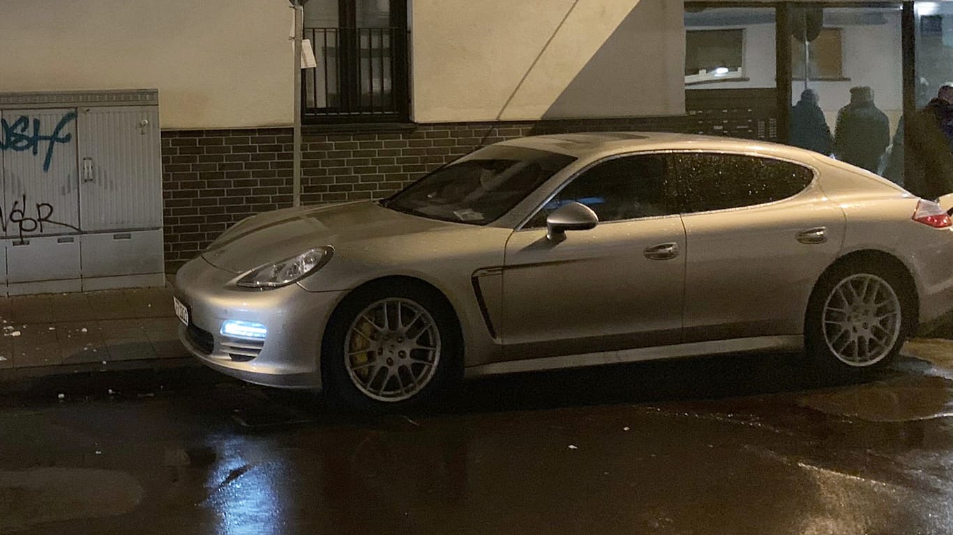 Ein Porsche mit einem Einschussloch steht in einer Straße: Wie die Polizei mitteilte, soll der Täter am Donnerstagabend in einem anderen Auto geflüchtet sein.
