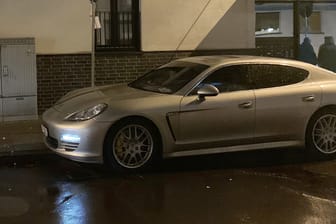 Ein Porsche mit einem Einschussloch steht in einer Straße: Wie die Polizei mitteilte, soll der Täter am Donnerstagabend in einem anderen Auto geflüchtet sein.