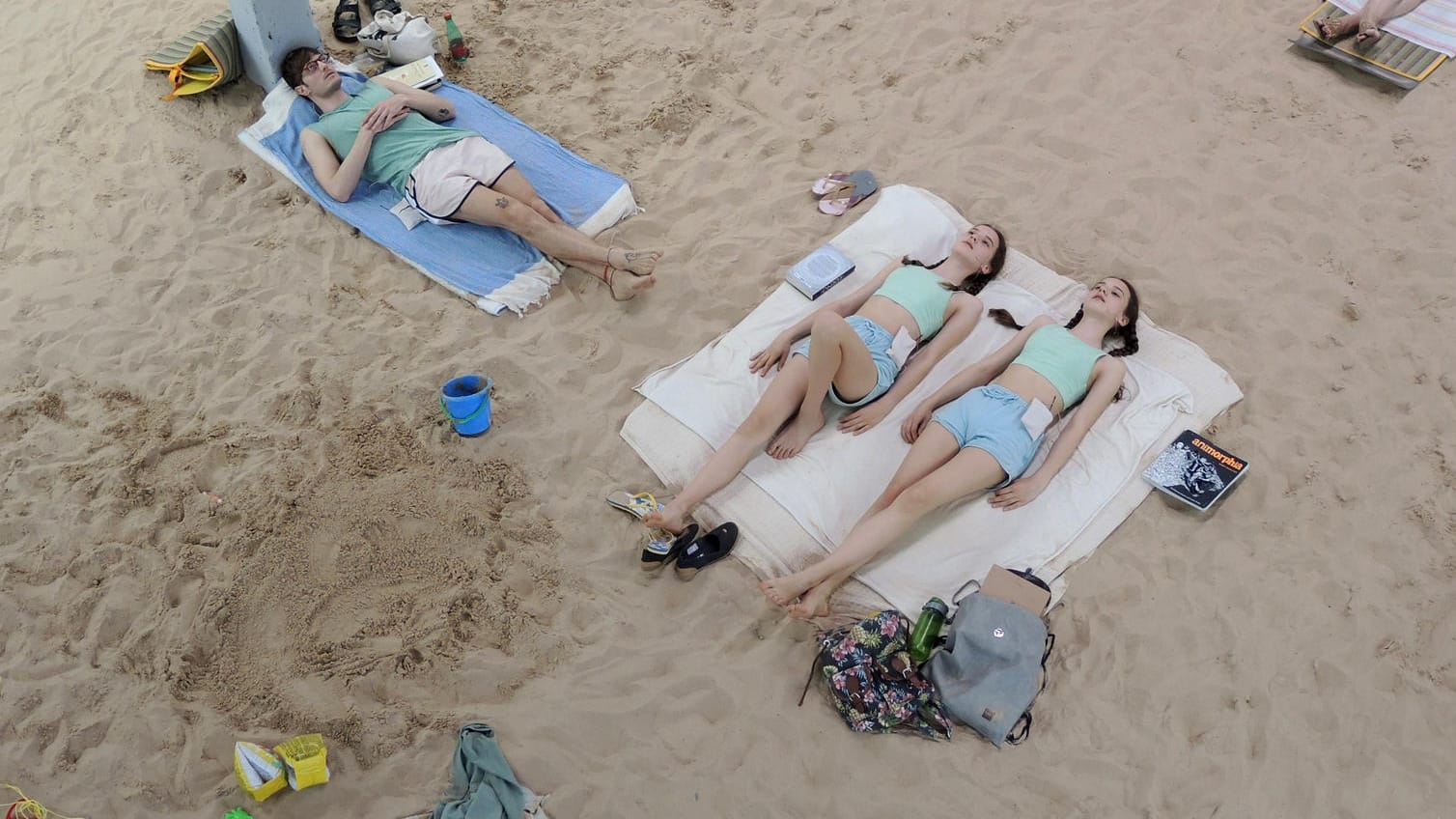 Blick auf die Performance "Sun & Sea (Marina)" der litauischen Künstlerinnen Rugile Barzdziukaite, Vaiva Grainyte und Lina Lapelyte: Auf einem in einem alten Gebäude der Marine aufgeschütteten Strand liegen Sänger, die unter anderem über den Klimawandel singen.