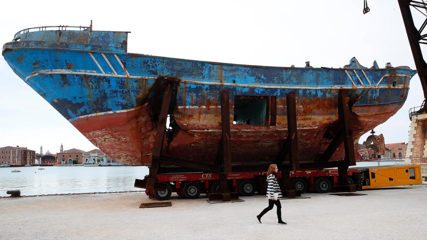 Eine Frau geht an dem Wrack eines Fischerbootes vorbei, das 2015 mit 700 Migranten an Bord im Mittelmeer versunken ist: Das Boot ist Teil einer Installation des Künstlers Christoph Büchel und wird unter dem Namen "Barca Nostra" (Unser Boot) ausgestellt.