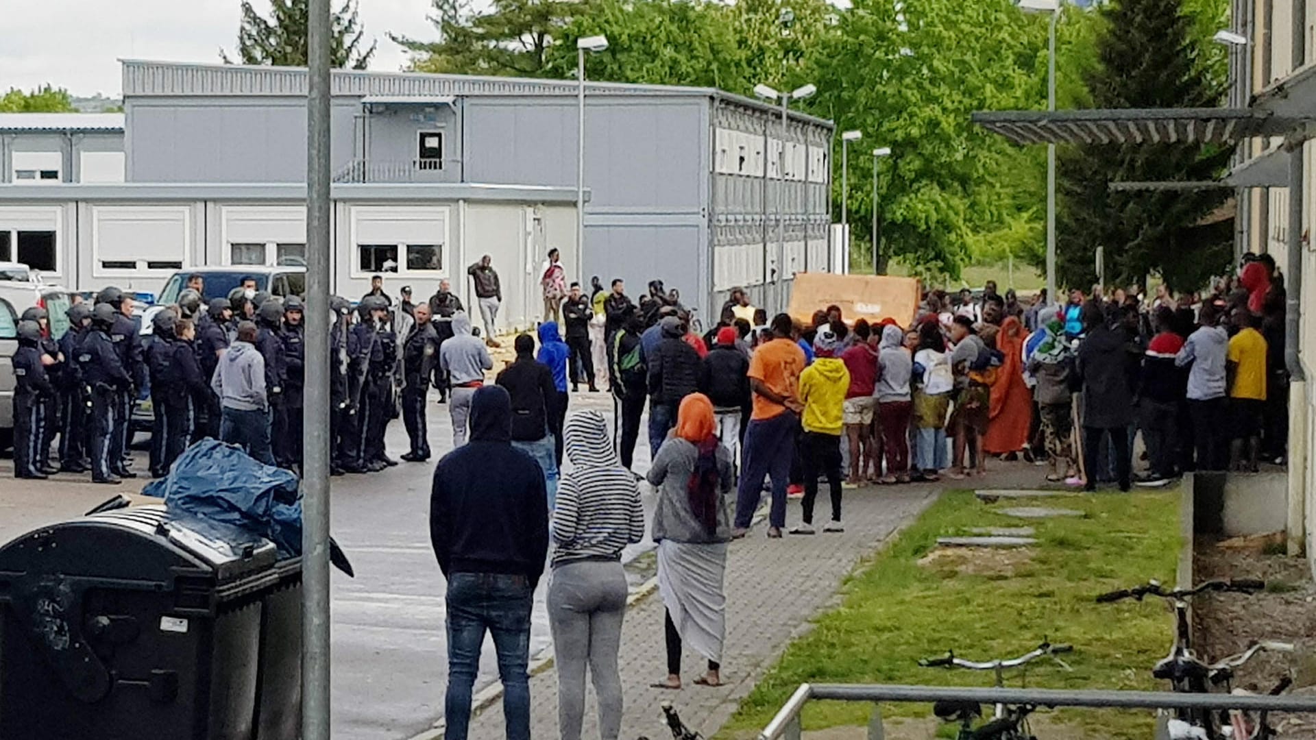 Ankerzentrum in Regensburg: Vor der Einrichtung steht eine große Gruppe bewohner, zahlreiche Polizisten sind zu sehen.