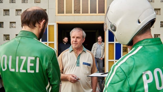 Georg Weiser (Joachim Król, M) im Gespräch mit zwei Polizisten in der Komödie "Endlich Witwer".