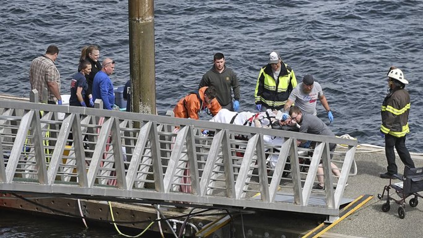 Rettungskräfte transportieren einen verletzten Passagier zu einem Krankenwagen in den Docks des George Inlet vor der Küste von Alaska.