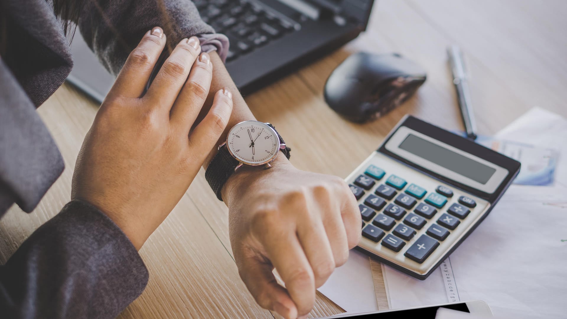 Arbeitnehmerin blickt auf die Uhr: Die tägliche Arbeitszeit darf acht Stunden nur in Ausnahmefällen übersteigen.