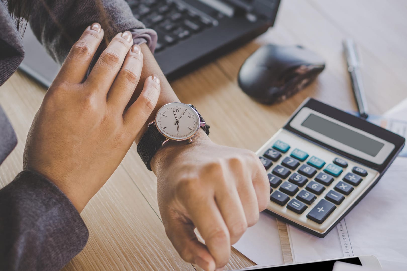 Arbeitnehmerin blickt auf die Uhr: Die tägliche Arbeitszeit darf acht Stunden nur in Ausnahmefällen übersteigen.