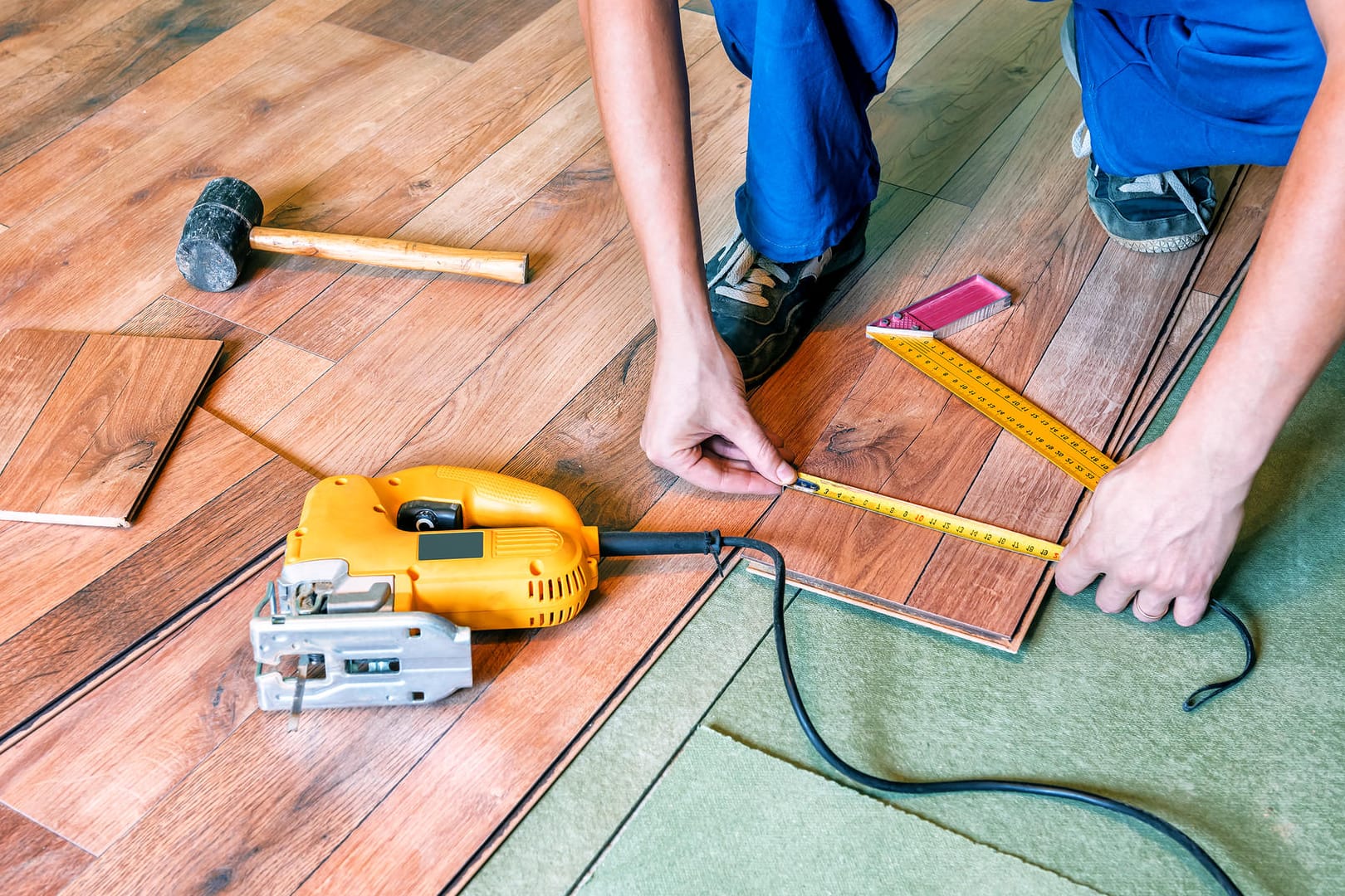 Handwerker verlegt Laminat: Die Wartezeit bei Handwerksbetrieben wird immer länger.