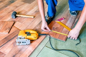 Handwerker verlegt Laminat: Die Wartezeit bei Handwerksbetrieben wird immer länger.