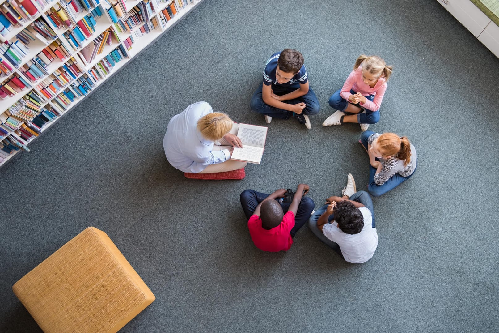 Grundschulkinder sitzen mit einer Betreuerin im Kreis: Die meisten Eltern wünschen sich mehr Nachmittagsangebote für ihre Kinder.