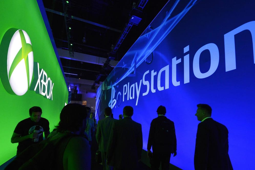 Besucher einer Spielemesse laufen an den Ständen von Xbox und Playstation vorbei: Die Konsolen-Konkurrenten Microsoft und Sony wollen ihre Kräfte bündeln.