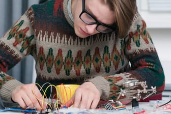 Ein junger Mann arbeitet mit Elektronikteilen: Kennen Sie die großen Erfinder?