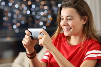 Eine Frau spielt am Smartphone (Symbolbild): Steam-Nutzer können ihre Spiele auf Android- oder iOS-Geräte streamen.