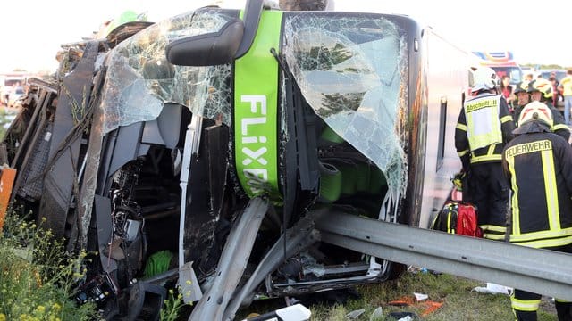 Einsatzkräfte der Feuerwehr an der Unfallstelle neben dem verunglückten Bus.