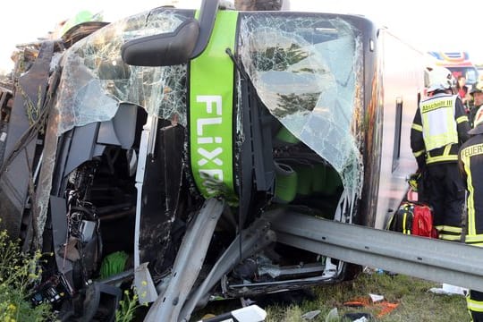 Einsatzkräfte der Feuerwehr an der Unfallstelle neben dem verunglückten Bus.