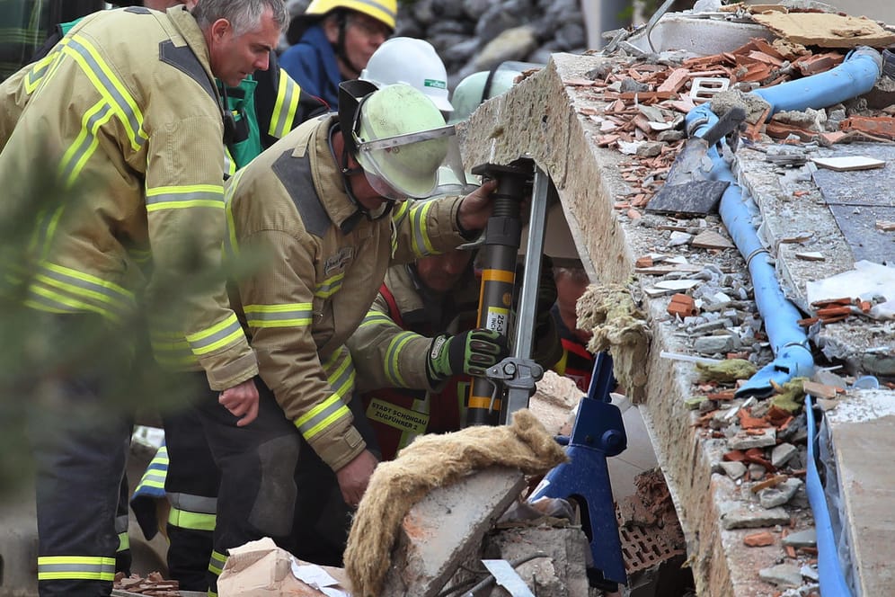 Rettungskräfte im Einsatz: Mit schwerem Gerät bahnen die Helfer sich den Weg durch die Trümmer – zwei Menschen werden nach der Explosion eines Hauses vermisst.