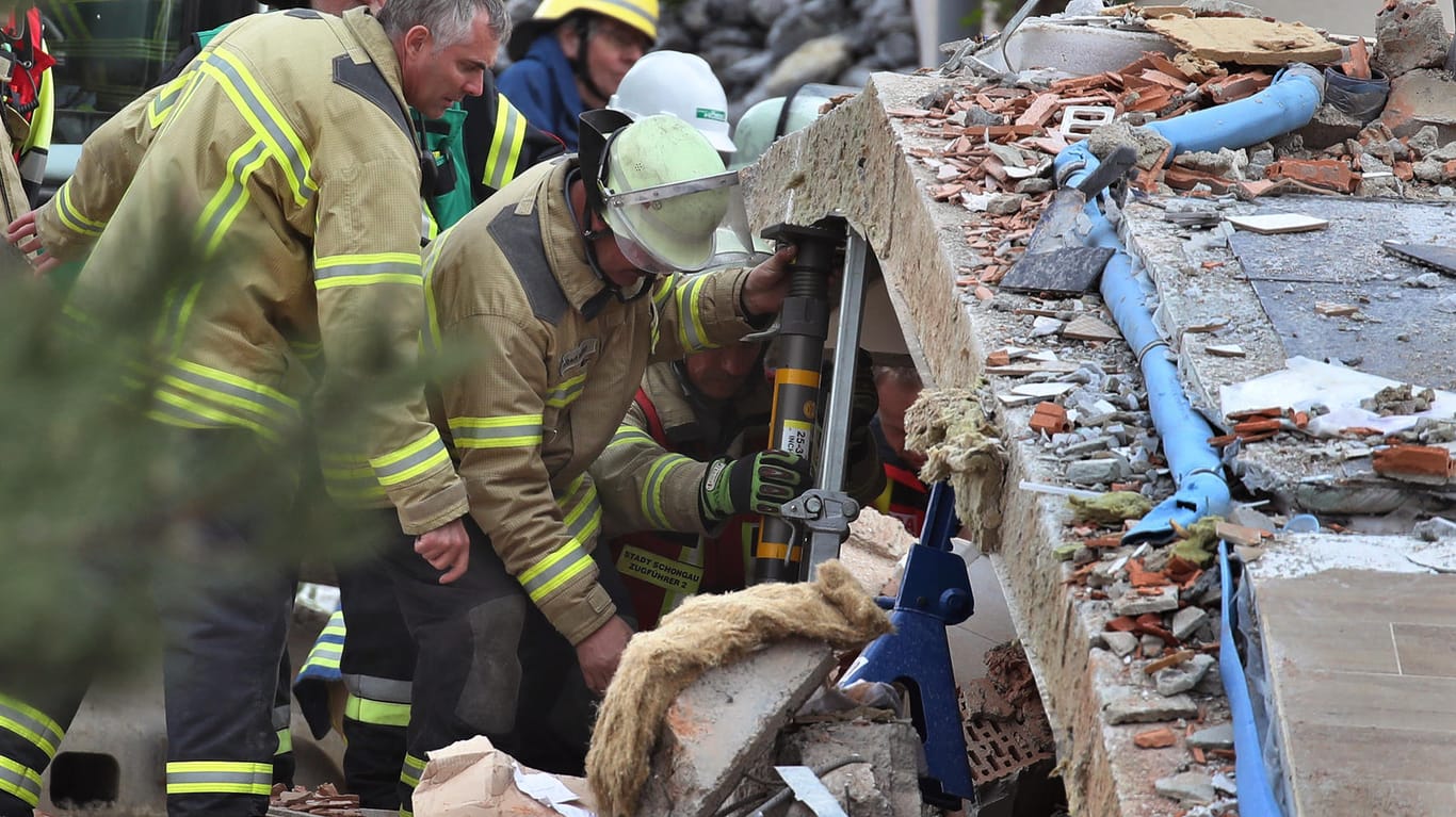 Rettungskräfte im Einsatz: Mit schwerem Gerät bahnen die Helfer sich den Weg durch die Trümmer – zwei Menschen werden nach der Explosion eines Hauses vermisst.