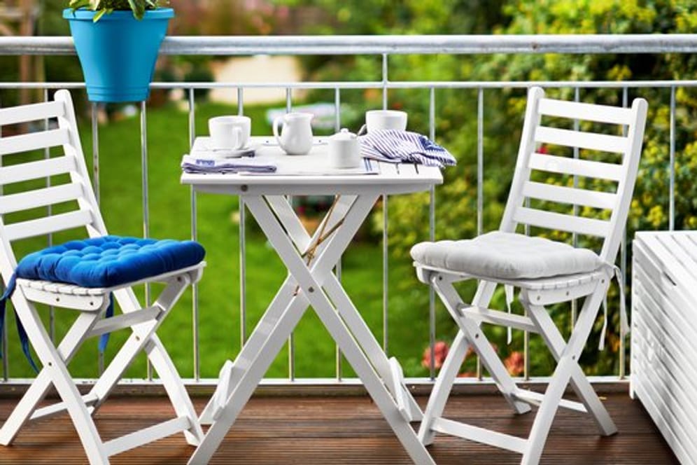 Blau macht als Akzentfarbe auf dem Balkon viel her: Es setzt sich von den dezenteren Farben für Möbel und Boden ab und harmoniert mit dem Grün der Bepflanzung.