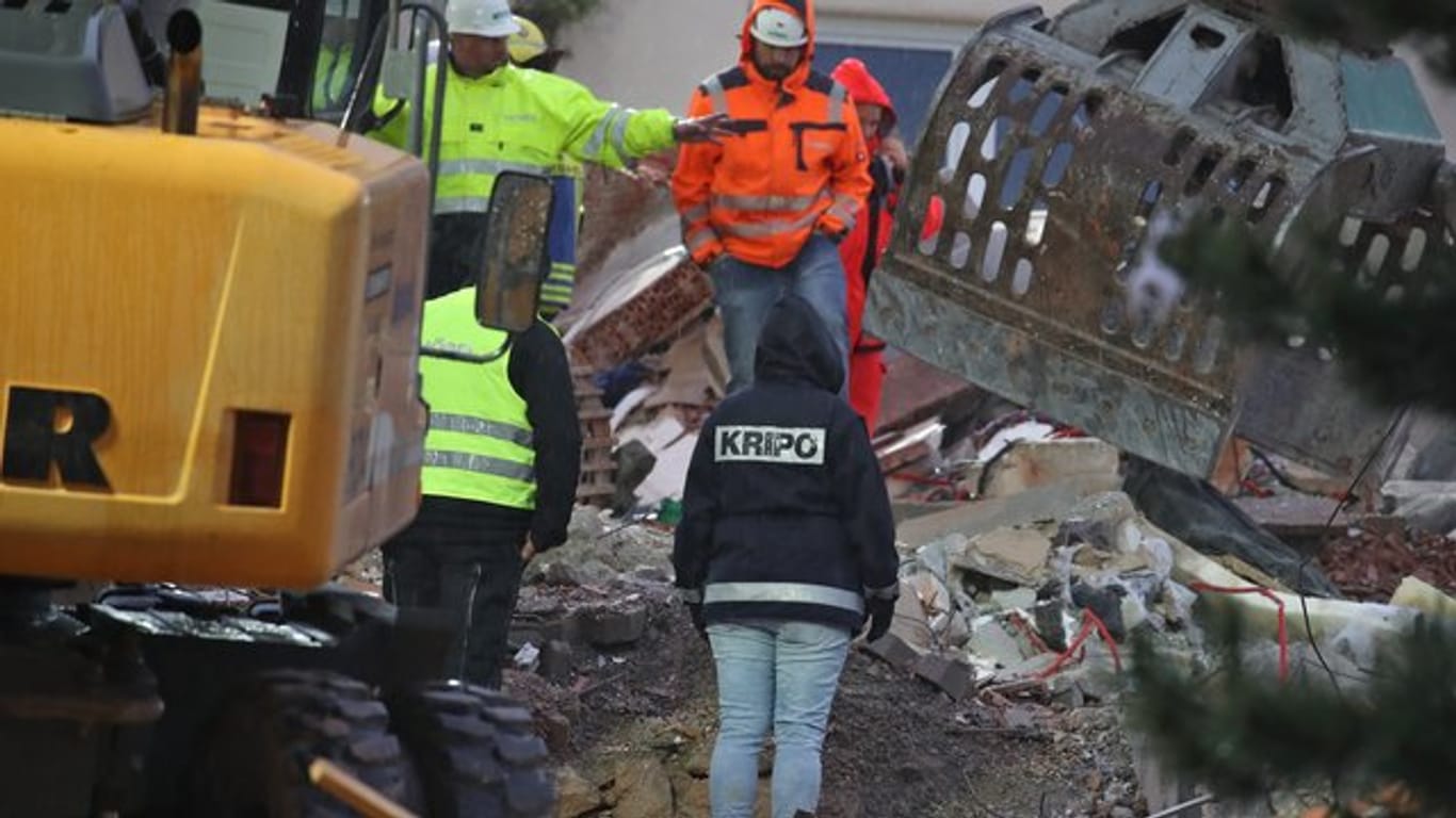 Eine Mitarbeiterin der Kriminalpolizei steht in den Trümmern eines zerstörten Hauses.