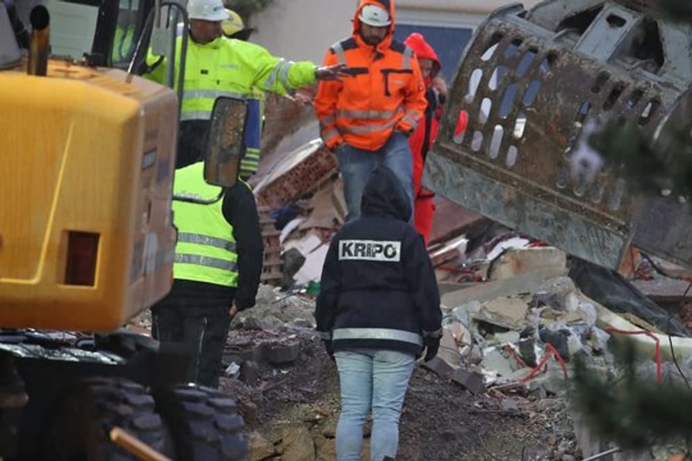 Eine Mitarbeiterin der Kriminalpolizei steht in den Trümmern eines zerstörten Hauses.