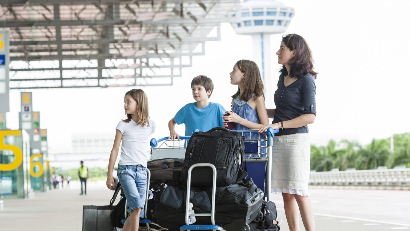 Familie steht vor Flughafen: Geht es um die Urlaubszeit, muss ein Arbeitgeber die Interessen verschiedener Mitarbeiter unter einen Hut bringen.