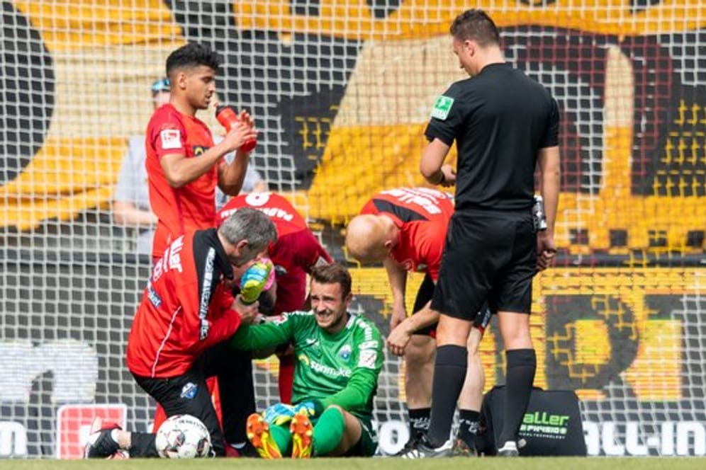 Paderborns Torwart Leopold Zingerle (M) muss nach einem Zusammenstoß mit Dynamos Moussa Koné behandelt werden.
