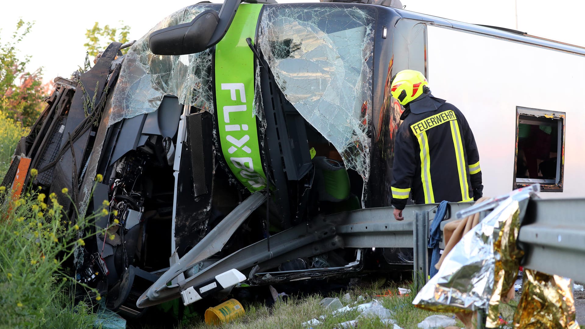 Einsatzkräfte der Feuerwehr stehen neben dem verunglückten Bus: Der Busfahrer ist weiterhin nicht vernehmungsfähig. (Archivbild)