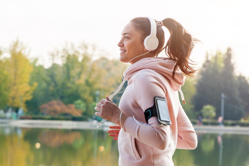 Eine Frau joggt und hört dabei Musik: Die Leistung kann gesteigert werden, wenn man seine Lieblingssongs beim Training hört.