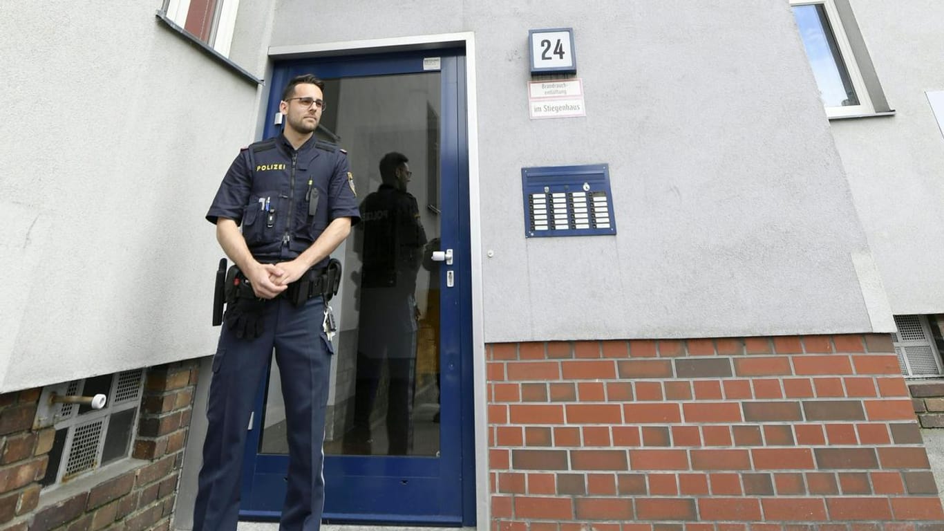 Ein Polizist steht vor dem Wohnhaus in Wien: Eine Mutter und ihre beiden Töchter wurden tot aufgefunden.