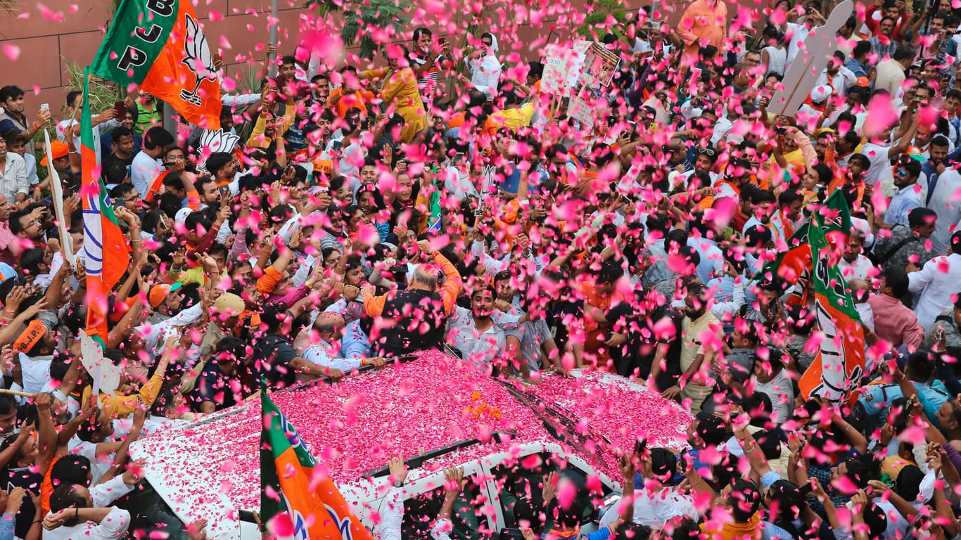 Amit Shah, Vorsitzender der Bharatiya Janata Partei (BJP), wird mit Blütenblätter bei seiner Ankunft am Parteibüro begrüßt. Trotz laufender Stimmzählung hat die BJP bereits ihren Sieg erklärt.
