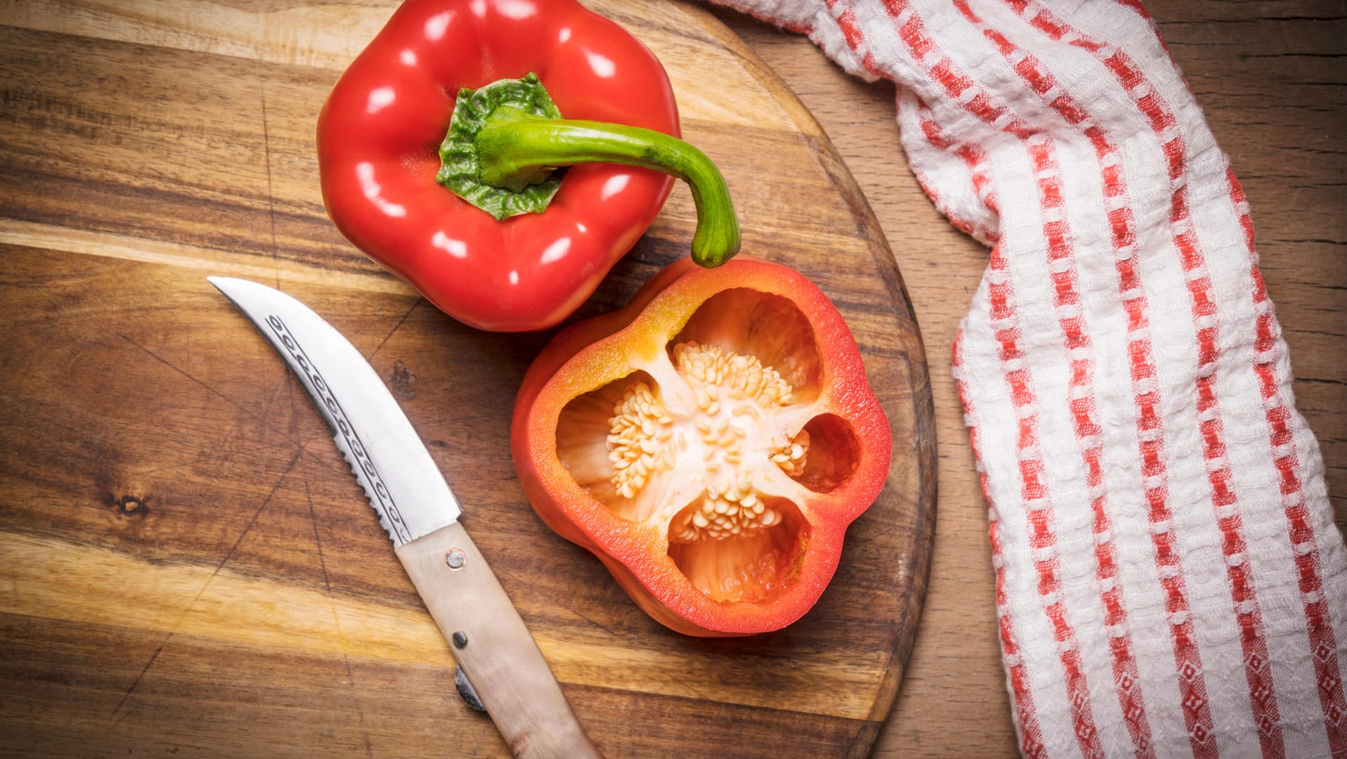 Rote Paprika auf einem Schneidebrett: An der Farbe erkennt man den Reifegrad der Früchte.