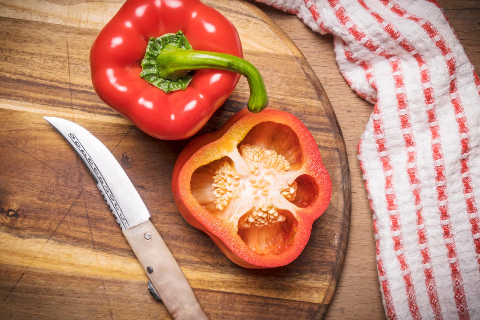 Rote Paprika auf einem Schneidebrett: An der Farbe erkennt man den Reifegrad der Früchte.